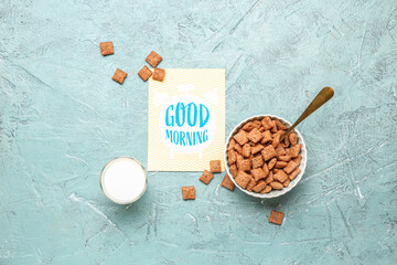 Card with text GOOD MORNING, glass of milk and corn pillows on color background