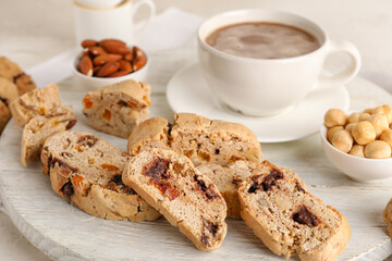 Wooden board with tasty biscotti cookies, nuts and cup of coffee, closeup