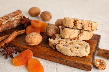 Wooden board with tasty biscotti cookies, walnuts, dried apricots and spices on light background,...