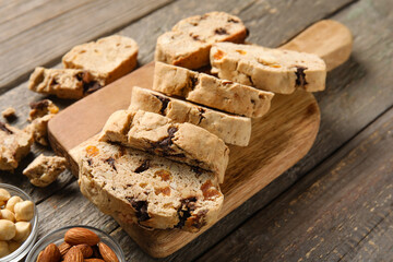 Board with delicious biscotti cookies on wooden background