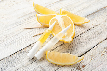 Cuticle oil pens and lemon on light wooden background