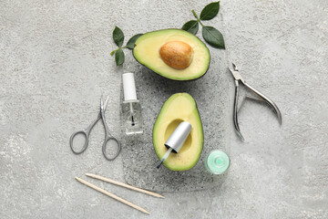 Composition with bottles of cuticle oil, manicure instruments and avocado on grunge background