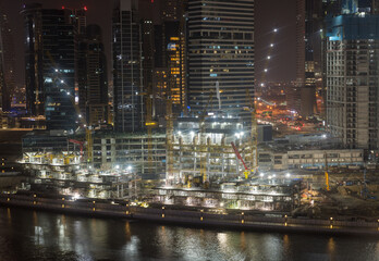 Fototapeta na wymiar Nighttime construction of new tower for apartments along canal in Business Bay of Dubai UAE