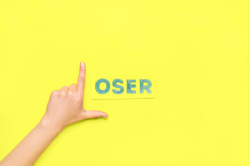 Woman showing loser gesture on yellow background