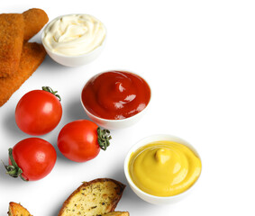 Bowls of ketchup, mayonnaise and mustard with snacks isolated on white background
