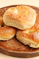Plate of tasty bagels with sesame seeds on beige background, closeup