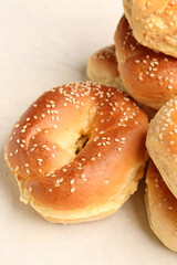 Tasty bagels with sesame and cream cheese on light background, closeup