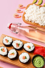 Composition with tasty sushi rolls and ingredients on pink background, closeup