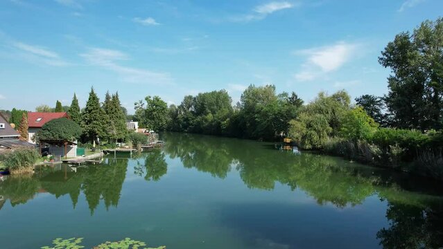 Aerial drone shot flying above a river with holiday homes on the side