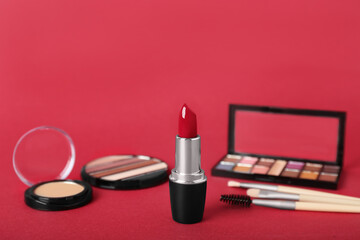 Set of decorative cosmetics with lipstick on red background