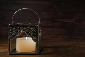 Muslim lamp with burning candle on dark wooden background