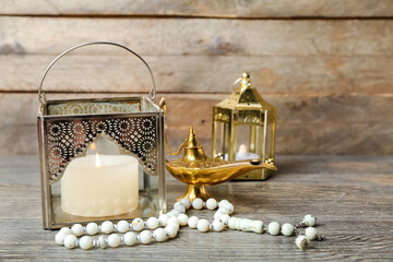 Muslim lamps with prayer beads on wooden background