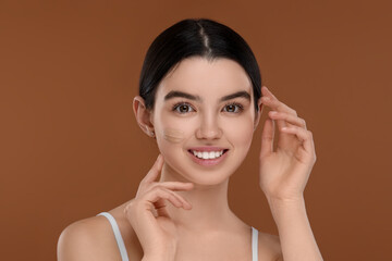 Teenage girl with swatch of foundation on face against brown background