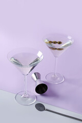 Glasses of martini with olives, bar spoon and jigger on color background
