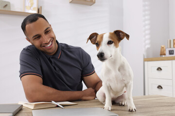 Young man with Jack Russell Terrier at desk in home office