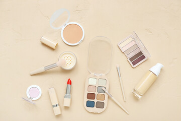 Decorative cosmetics with eyeshadows and brushes on beige background