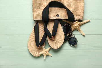Bag with flip-flops, sunglasses and starfishes on green wooden background