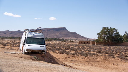 Vehicle wreck beside the highway near Kebili, Tunisia, with the Atlas Mountains in the background