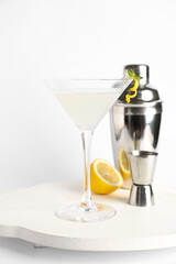 Glass of tasty martini, jigger, shaker and lemon on white background