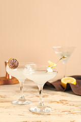 Glasses of martini with lemon on light wooden table