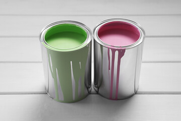 Cans of pink and green paints on white wooden table