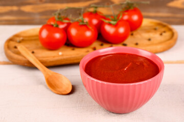 Bowl with tasty tomato paste on table