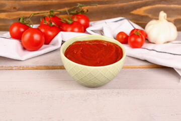 Bowl with tasty tomato paste on table