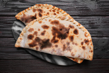 Delicious calzones on wooden table, top view
