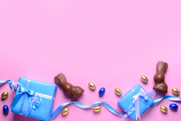 Chocolate bunnies, Easter eggs in foil and gift boxes on pink background