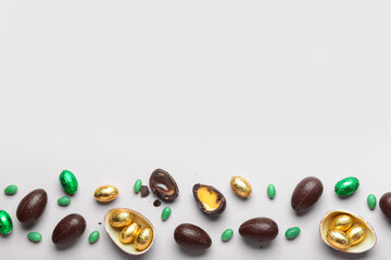 Sweet chocolate Easter eggs and candies on light background