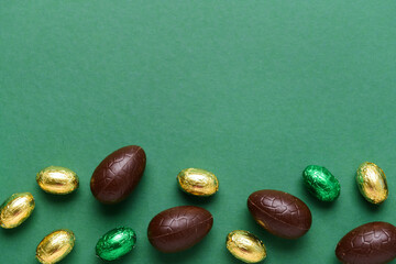 Chocolate Easter eggs and candies on green background