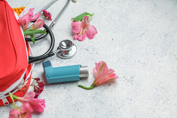 First aid kit with asthma inhaler, stethoscope and flowers on grunge background, closeup