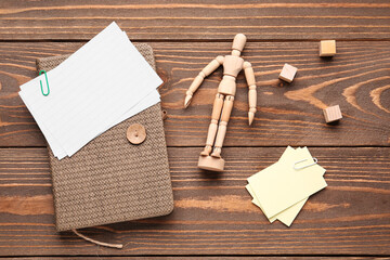 Composition with paper sheets, notepad and figurine on wooden background