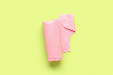 Pink roll of garbage bags on green background