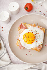 Delicious sandwich with fried egg and bacon on light background