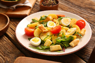 Plate of tasty potato salad with eggs and tomatoes on wooden background