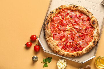 Cardboard box with delicious pepperoni pizza and ingredients on orange background