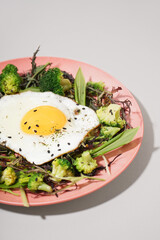 Plate with tasty fried egg and salad on grey background