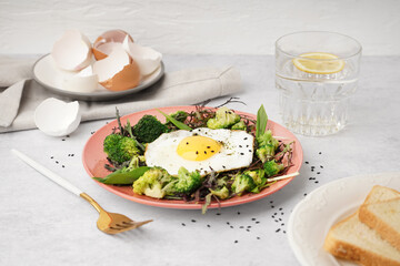 Plate with tasty fried egg and salad on table