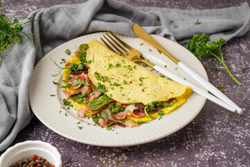 Tasty omelet with ham and greens on grey grunge background