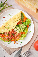 Tasty omelet with vegetables on light table