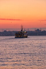 The ferry carrying the sunset and its passengers on the Bosphorus of Istanbul