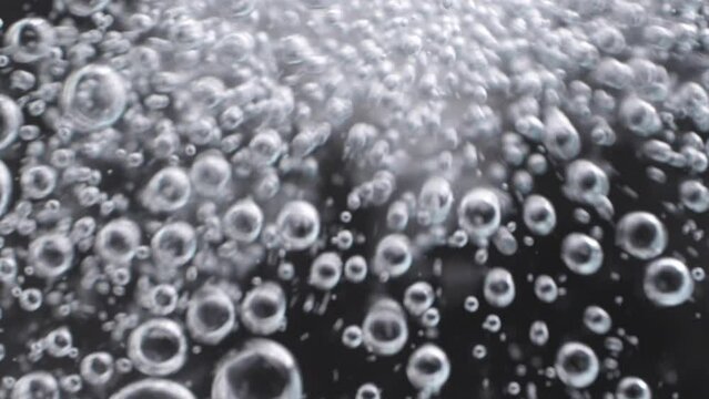 Top view closeup blur scene on chaotic moving pattern of white bright bubble isolated on black background, texture of soda water when gas release, fizz medical drink from antacid pill