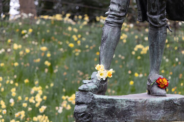 Statue of a famous Irish person with flowers on their shoes in Dublin Ireland 