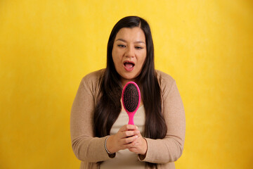 Latin adult woman with very long straight hair suffers from hair loss looking at the brush how many...