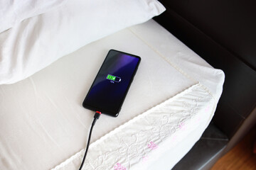 Charging smart phone with USB cable on the bed