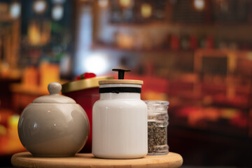 Mugs of sugar and salt containers style vintage over a table in night restaurant with selective focus and bokeh background