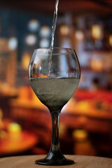 Vertical view of close up of glass while the wine is falling in the glass with wine in action 