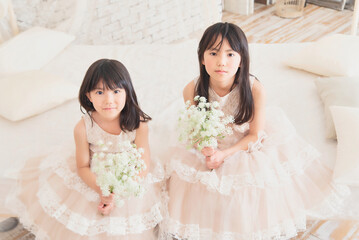 Obraz na płótnie Canvas ドレスを着て花を持つ姉妹