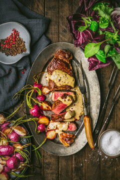 Steak au poivre sliced on platter with roasted radishes